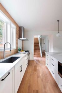 A view of the galley style kitchen with windows filtering the sunlight.