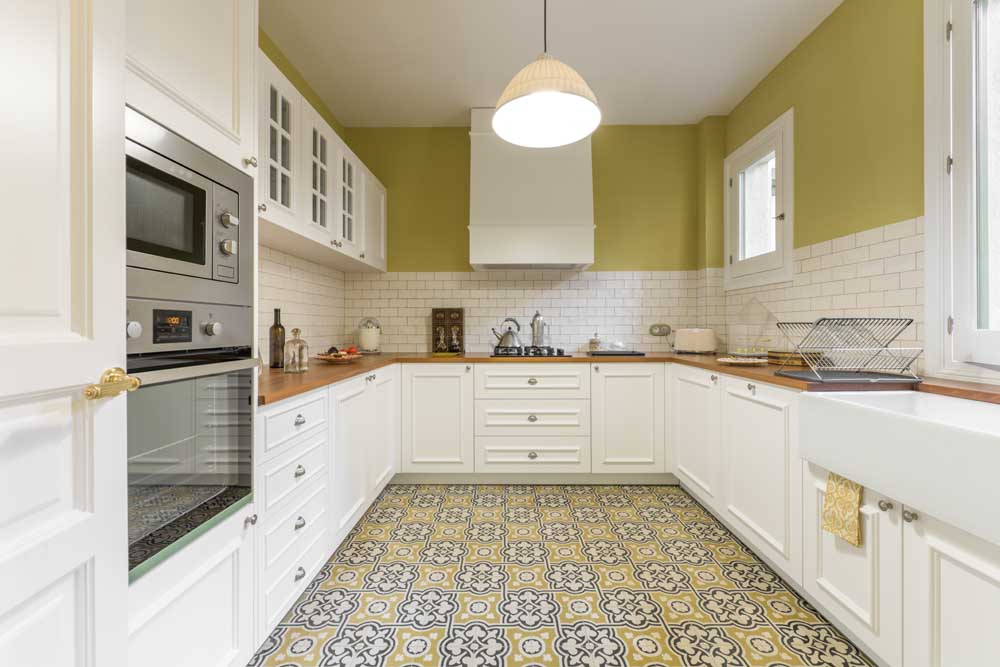 Vintage-style kitchen furnished in a u-shaped white lacquered wood with wooden countertop, white tiles and hydraulic tile floor
