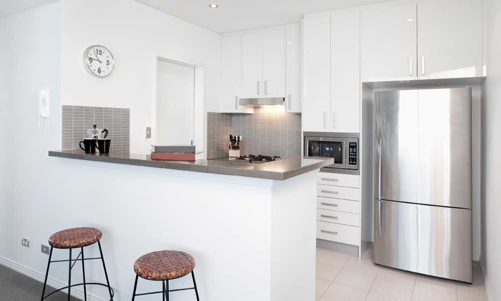 Modern white Kitchen in apartment with Polished Stainless Steel Appliances