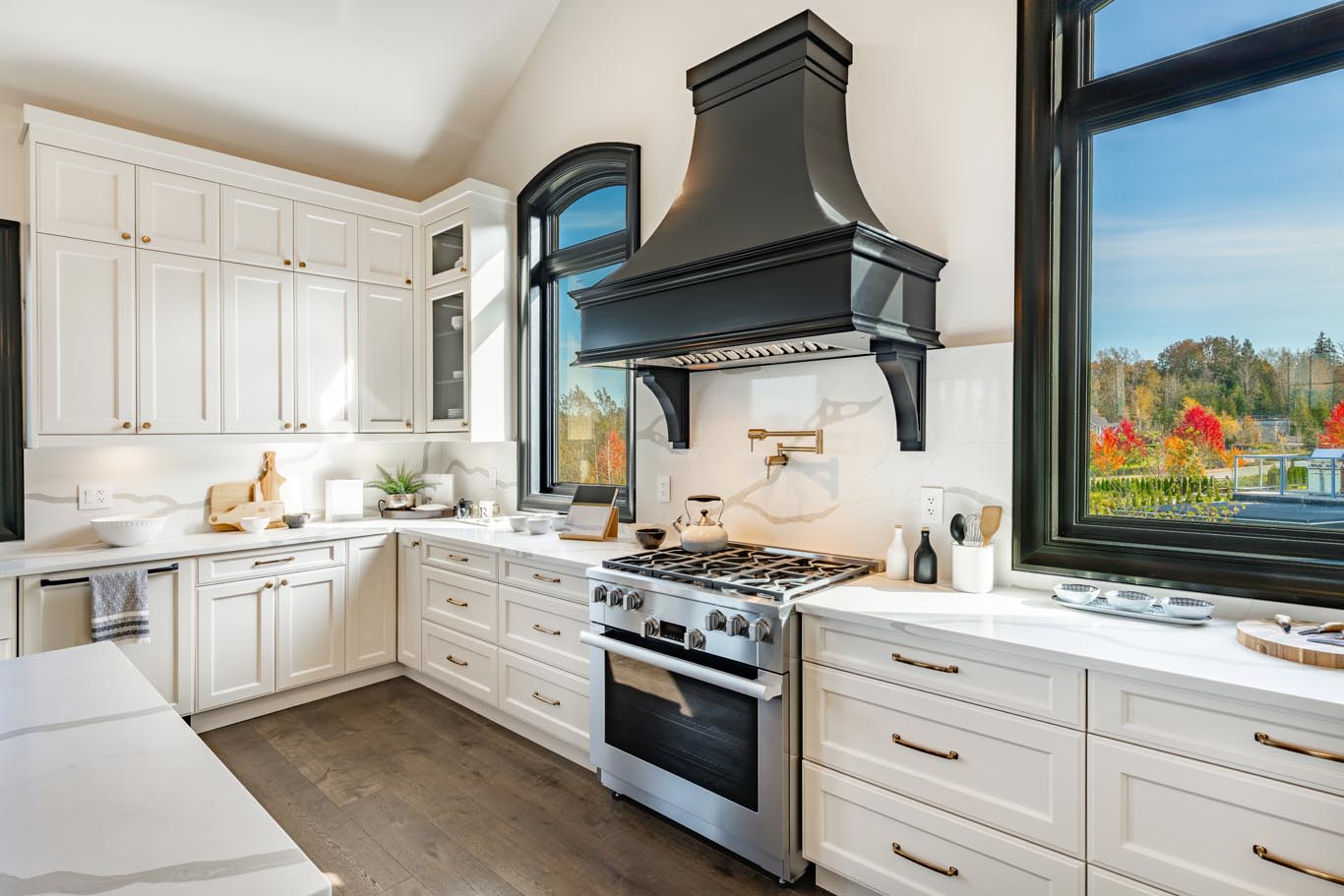 Huge spacious luxury kitchen staged clock beam ceiling dark hardwood slate flooring white cabinet center island with dining chairs long expansive countertop black wood framed windows view to mountains